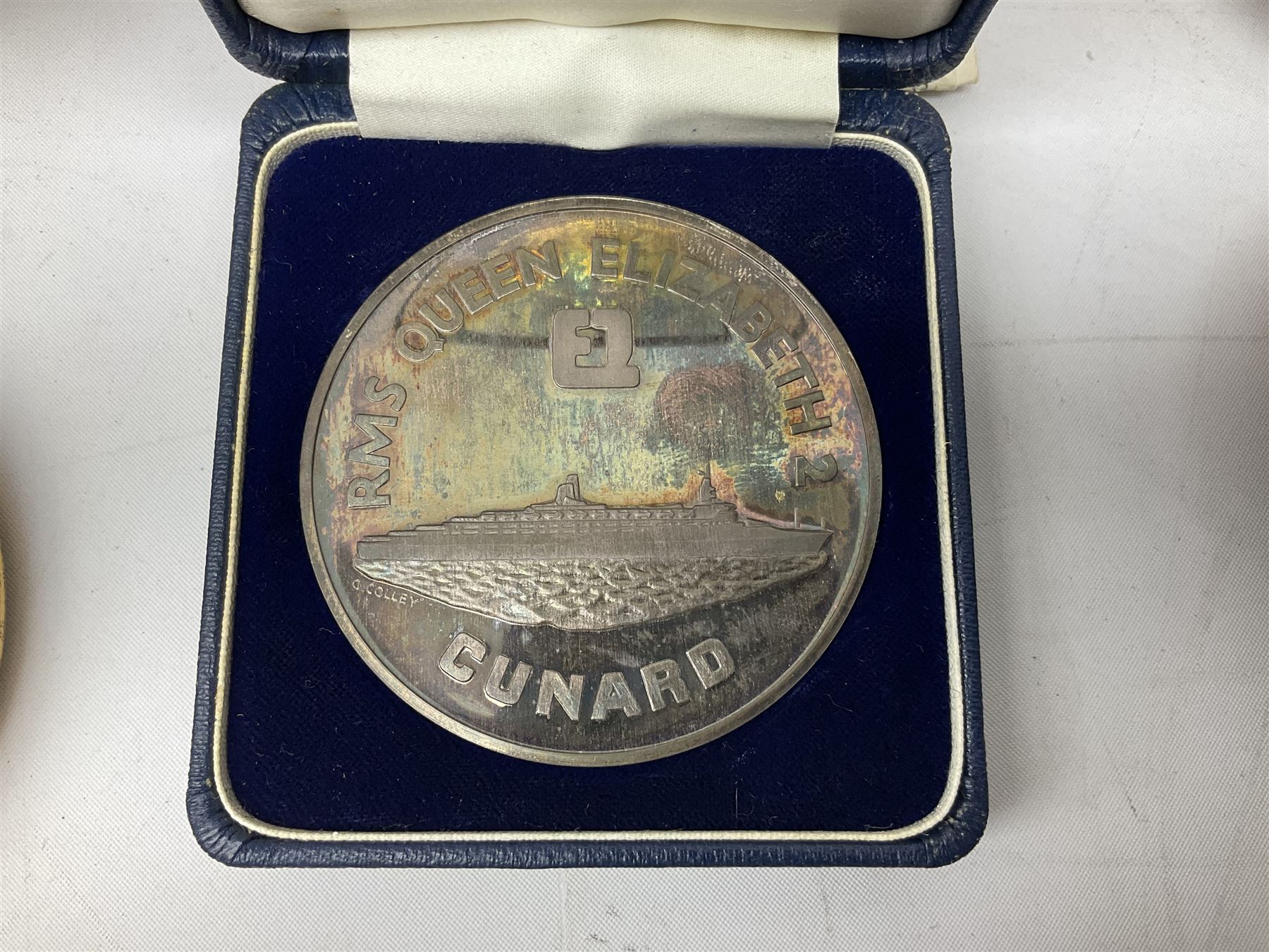 Silver 1969 Cunard RMS Queen Elizabeth maiden voyage commemorative medallion, in original Slade, Hampton & Son case with certificate, two Stratton R.M.S Queen Elizabeth mirror compacts, Stratton R.M.S Queen Mary compact, mid 20th century P&O Canberra Round World Voyage miniature globe, S.S Oriana ash tray modelled as a barrel, Norah Wellings sailor doll, and other maritime and shipping memorabilia 