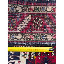 Northwestern Persian Heriz hand-knotted runner, dark indigo field with a series of linked stepped medallions in madder red, ivory, and green, flanked by angular floral motifs, within a madder red border of stylized rosettes and geometric vine motifs 405cm x 95cm