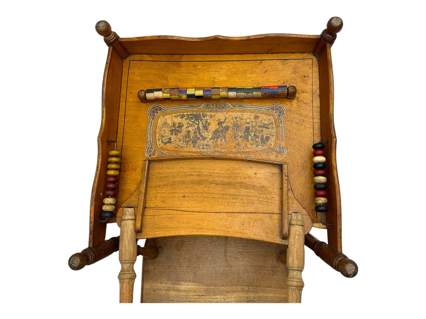 Late 19th century American oak child's metamorphic high chair and play table, carved spindle backrest with pierced splat, detachable tray with abacus and hand painted pastoral decoration, on turned supports with metal wheels