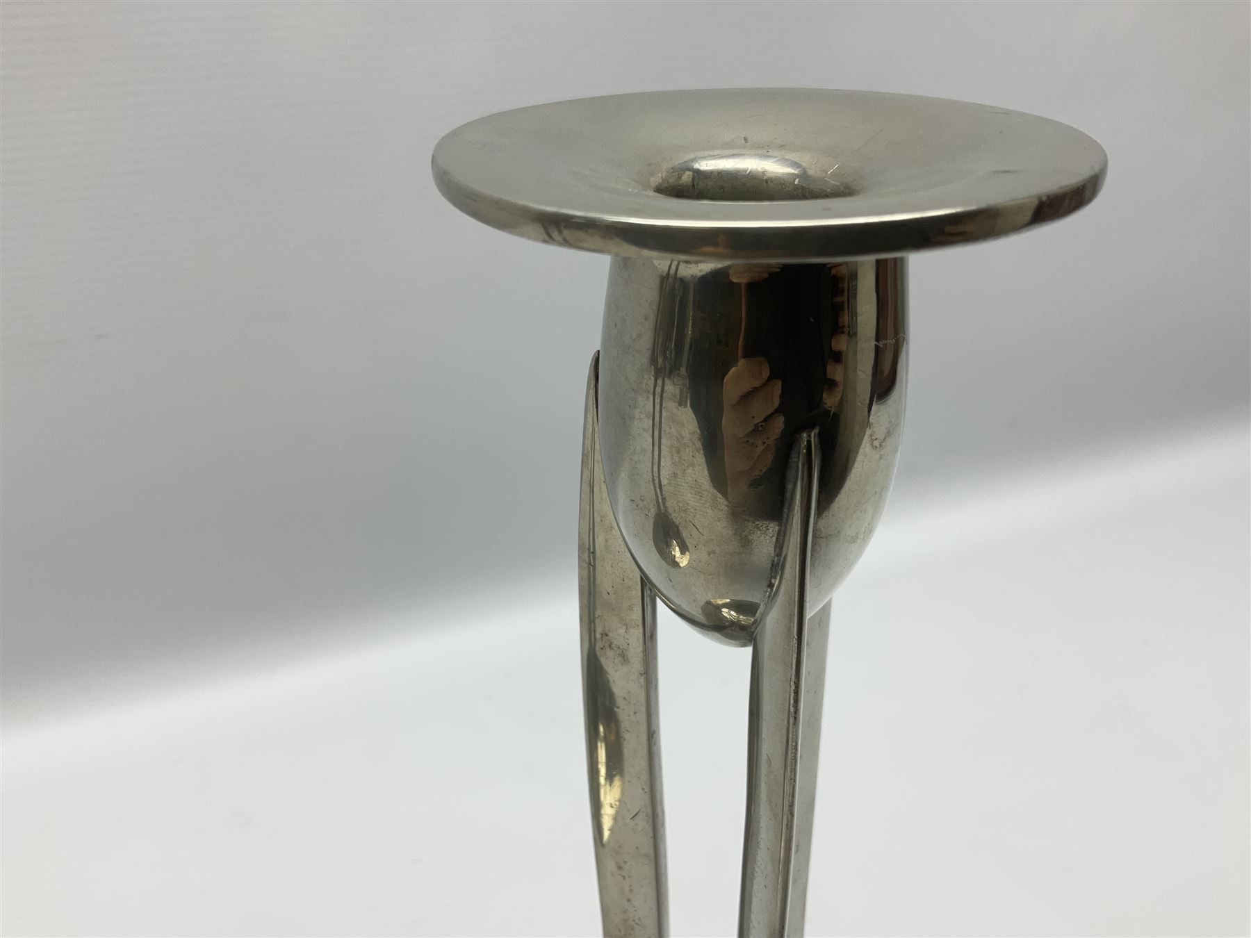 Archibald Knox (1864-1933) for Liberty & Co, pair of Tudric pewter candlesticks, the bud shaped sockets raised upon three angular fin supports and a slightly domed circular base with cast stylised foliate decoration, each stamped beneath Tudric 0223, H30cm