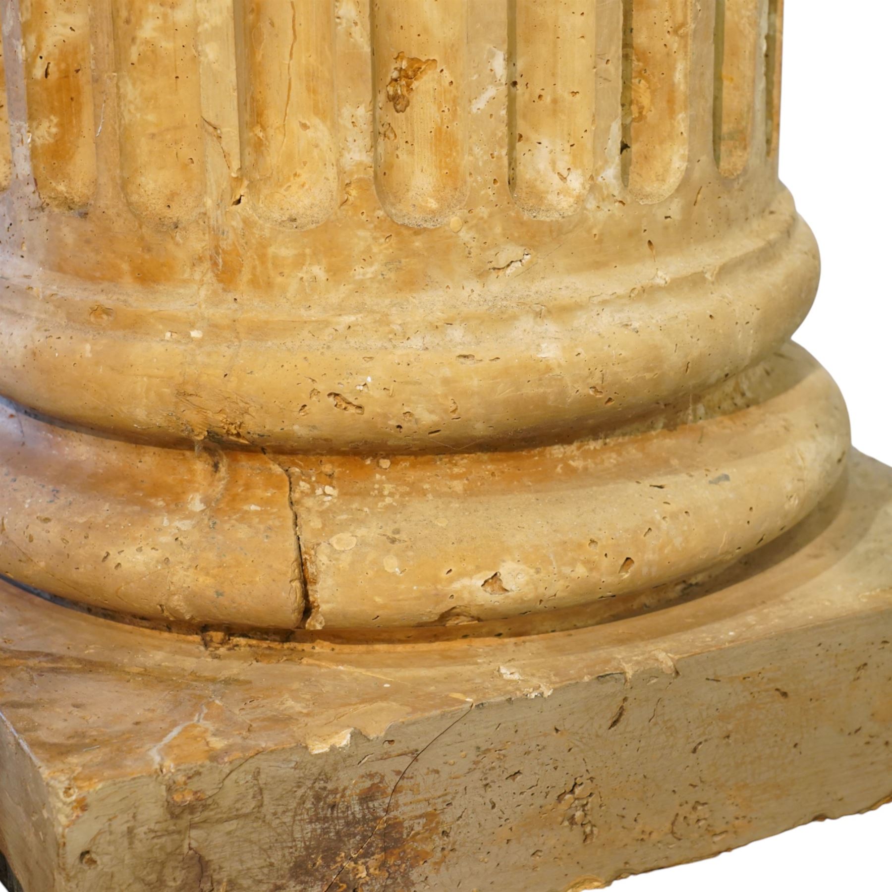 A pair of early 20th century Italian Neoclassical pedestal columns of simplified Doric type; each of fluted cylindrical form in composite stone, finished to evoke weathered limestone or travertine, raised on square plinth bases