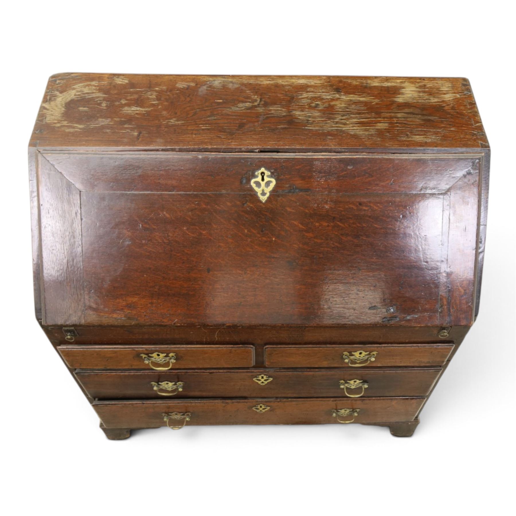 Georgian oak bureau, fall front with pierced brass escutcheon and handles, revealing a fitted interior, above two short over two long drawers, raised on bracket feet