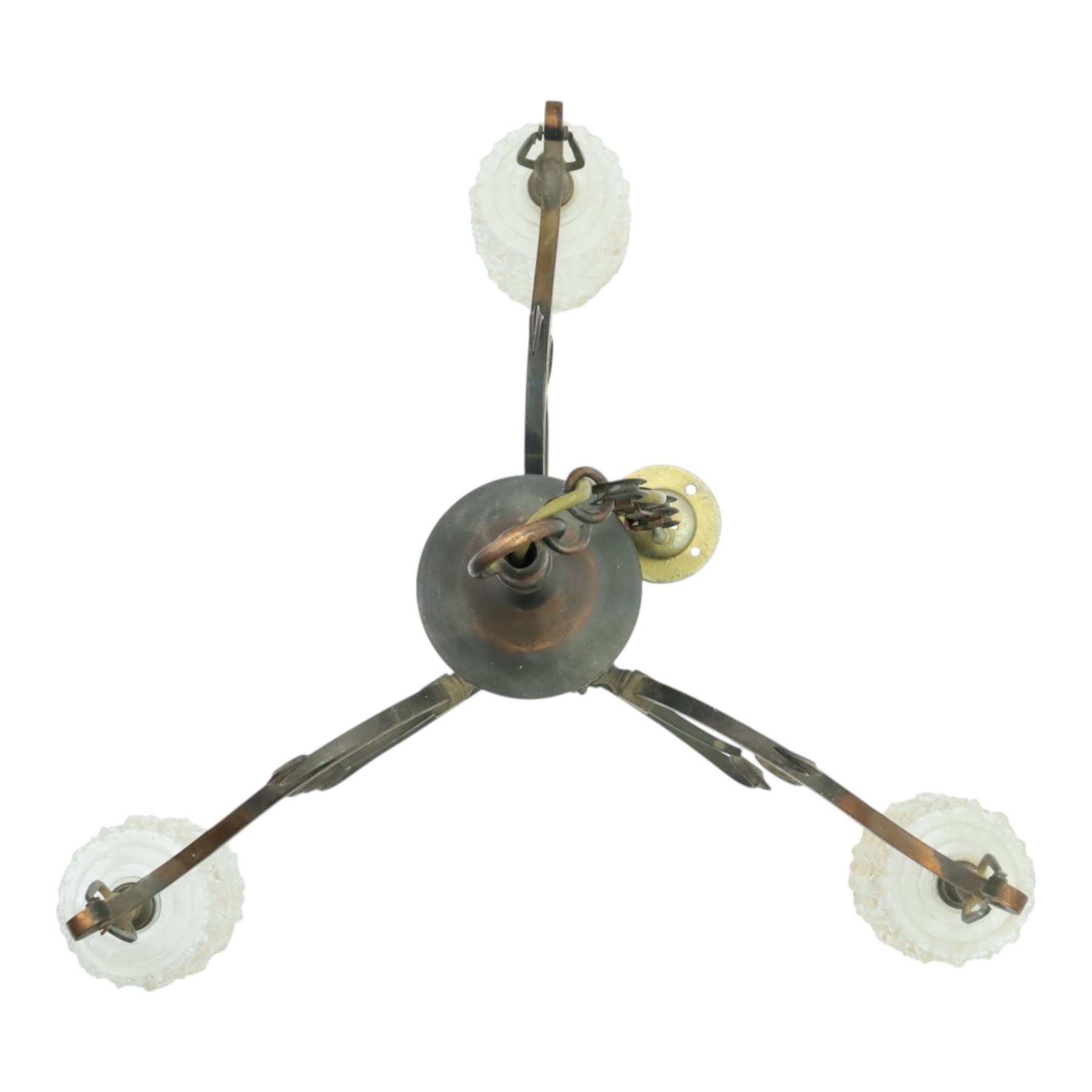 Art Nouveau copper three branch chandelier, turned central column with foiliate collar, issuing three scrolling strapwork arms, fitted with cut glass pendant shades, suspended from a chain