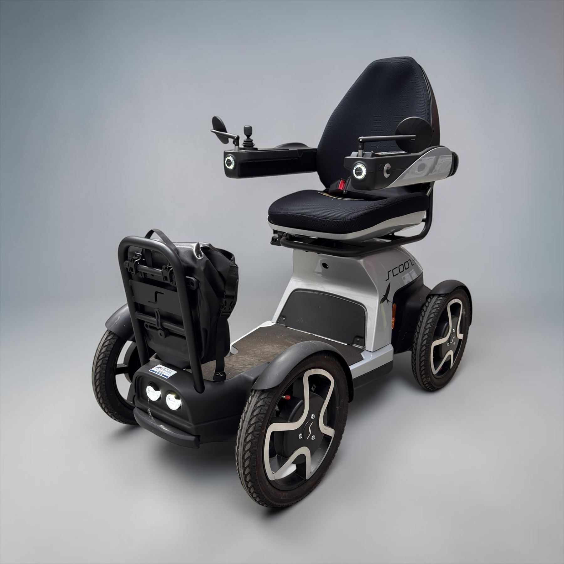 TGA Scoozy - mobility scooter, four wheel model with joystick controls, front storage bag, lights and grey and black bodywork.

