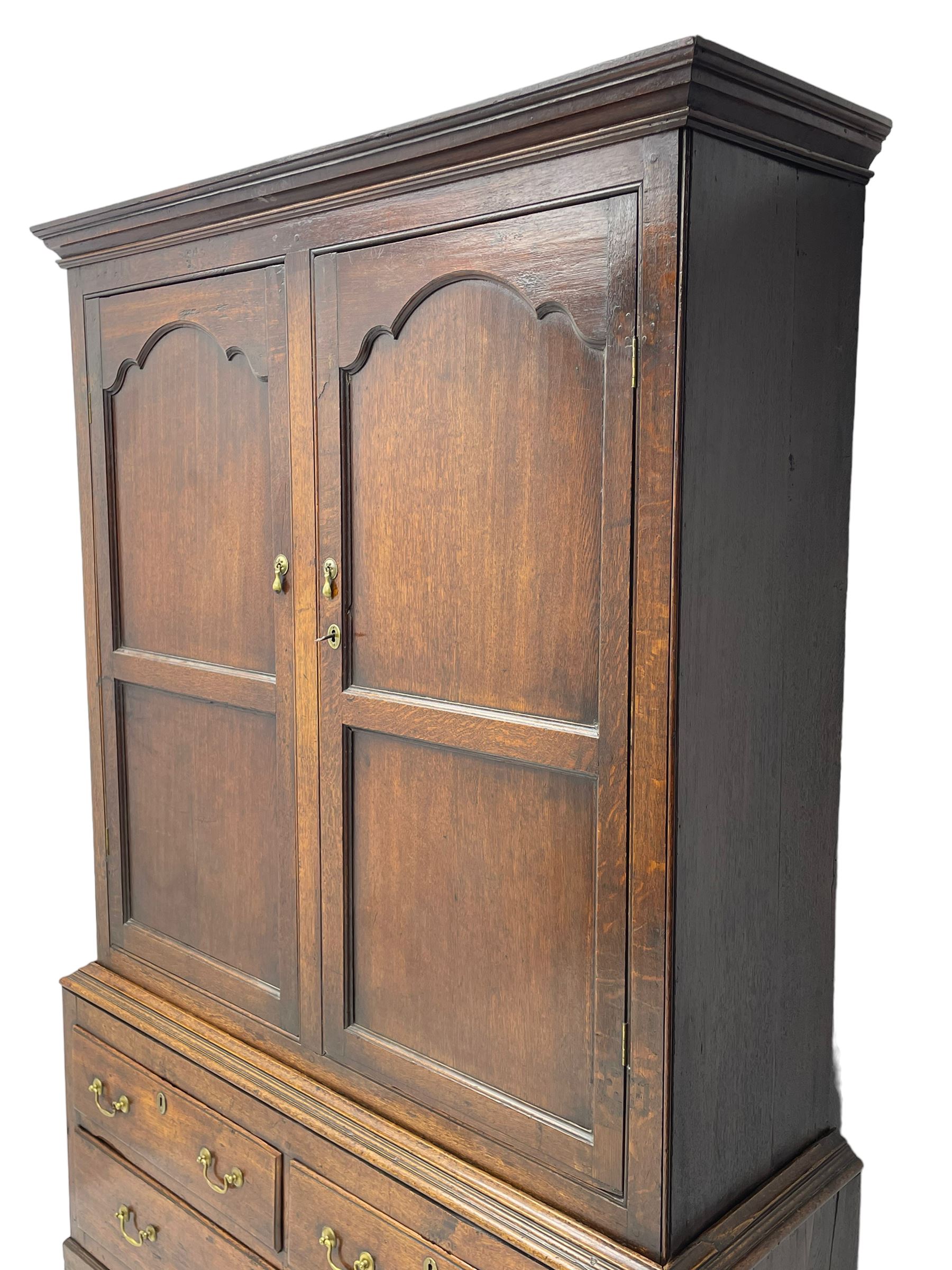 George III oak livery cupboard, projecting moulded cornice over two panelled doors, the upper panels within stepped ogee and arched moulded frame, the interior fitted with a single row of wooden hooks, two short and one long drawers, on bracket and return skirted base 