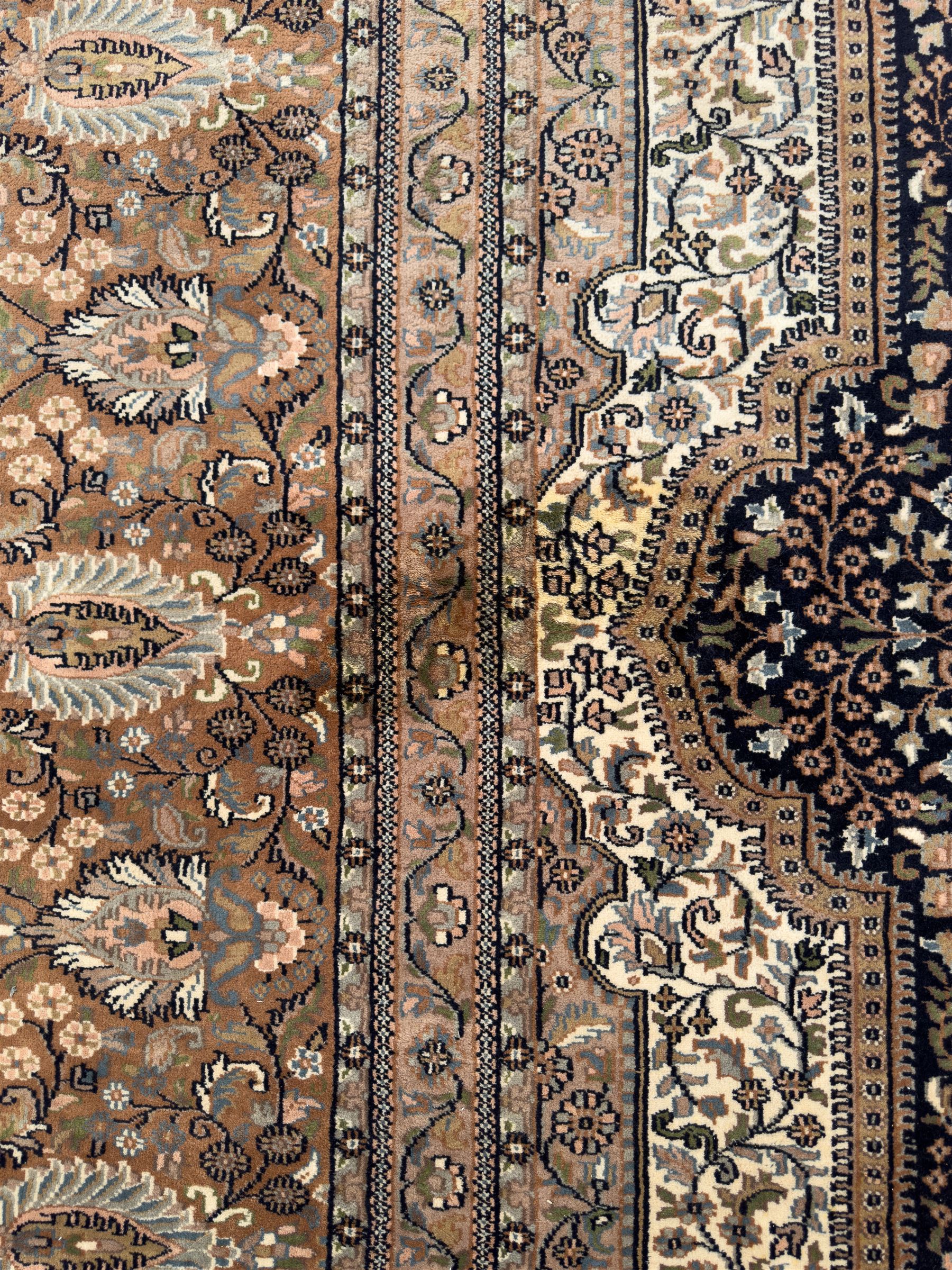 Large Persian indigo ground rug, the busy field decorated with trailing branches and flower heads, peach border decorated with palmettes -