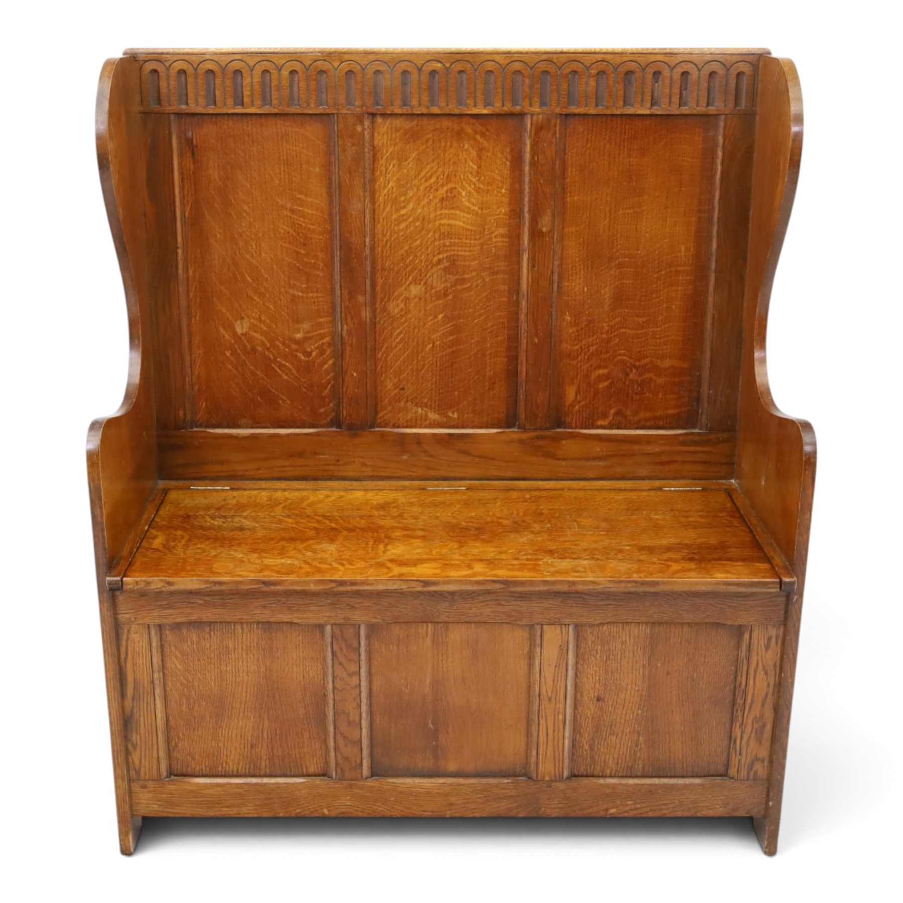 Early 20th century oak box settle, panelled back with arcaded carved rail, swept sides and arms, hinged seat with storage, panelled front