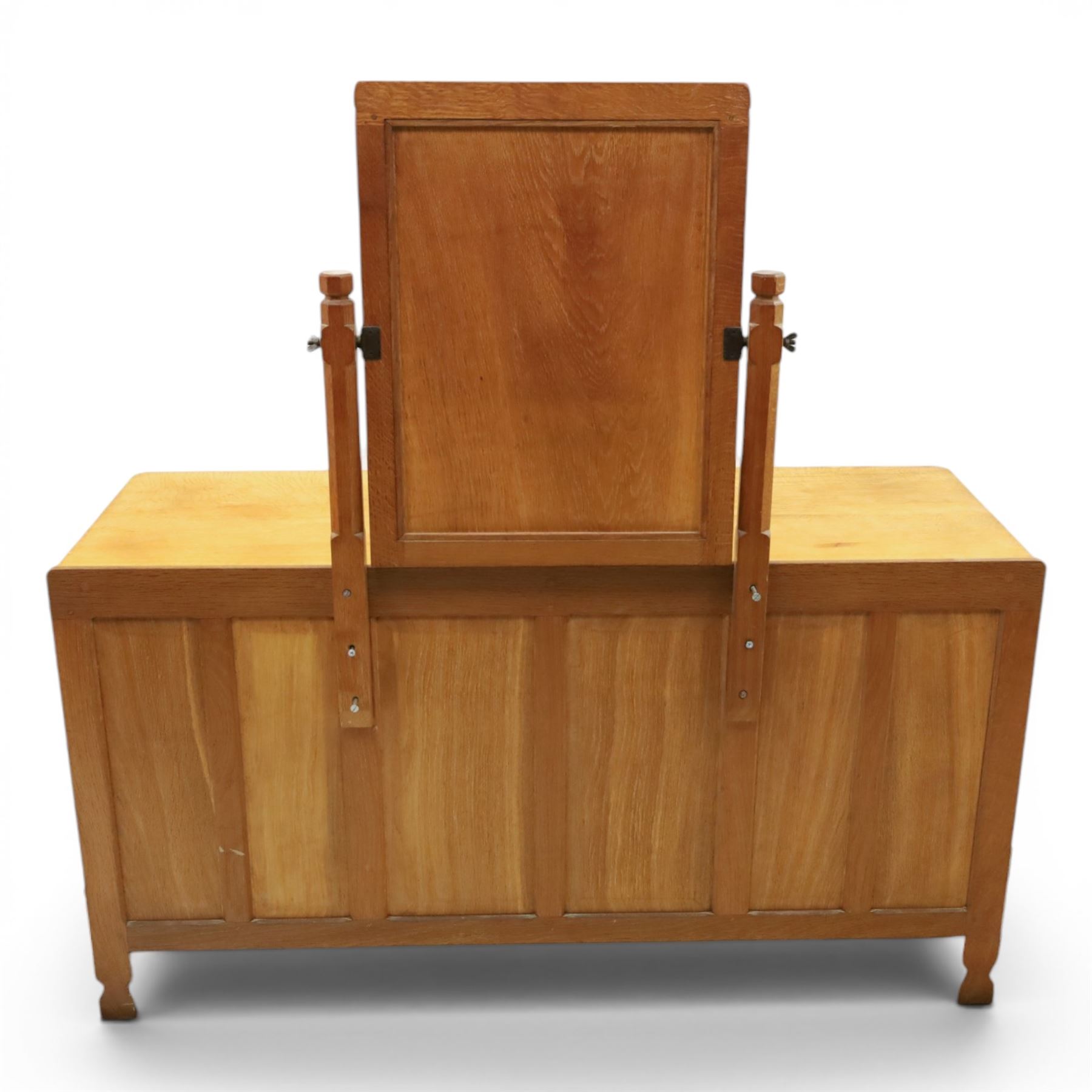 Mouseman - adzed oak kneehole dressing table with mirror, the rectangular adzed top with raised back and canted corners with fixed central pivoting mirror with scallop-carved cresting rail, over an arched recessed kneehole flanked by three graduating drawers to each side with turned knob handles, raised on octagonal feet, with carved mouse signature, by the workshop of Robert Thompson of Kilburn