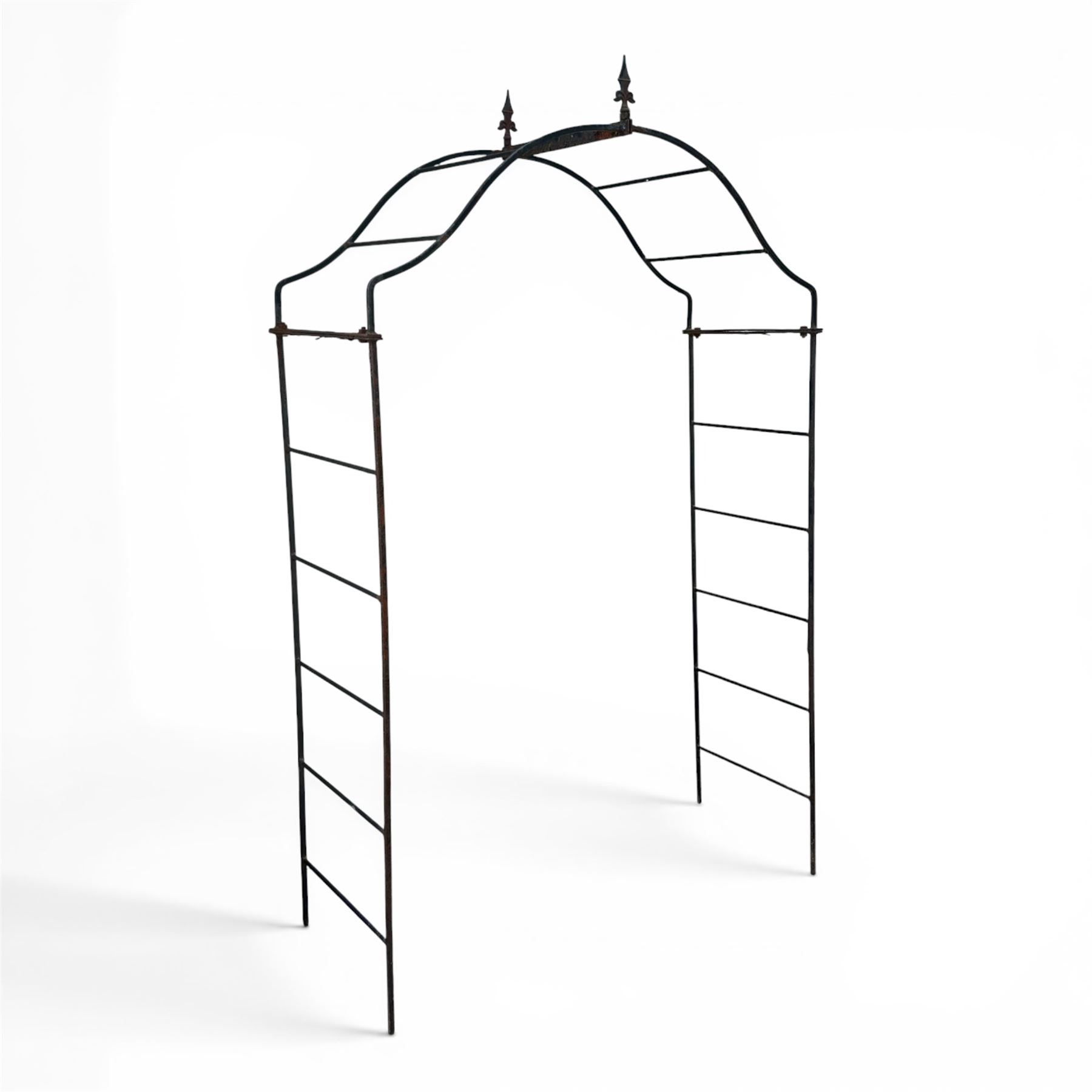 Antique wrought iron strapwork garden arch, with scroll form arched top with spearhead finials, over integral side trellis panels, in distressed black-painted finish