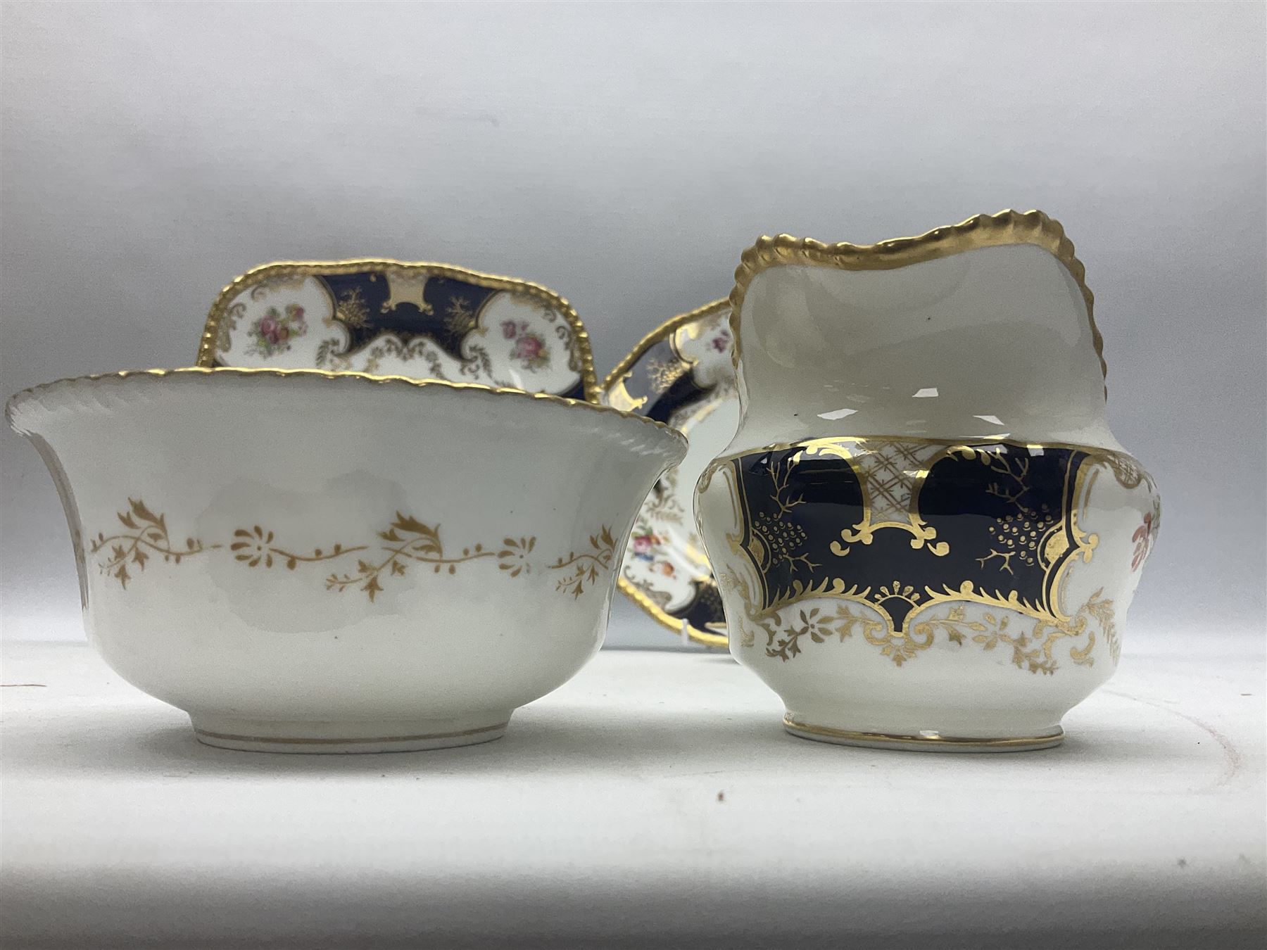 Coalport cobalt blue batwing pattern tea wares, decorated with finely enamelled floral sprays within gilt reserves, comprising teacup trio, coffee can and saucer and other cup and saucer, twin handled cake plate, milk jug and open sucrier, and circular plate retailed by T. Goode & Co London, pattern no Y2665,  all with green Coalport AD 1750 marks beneath, largest W26cm (11)