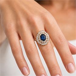 18ct gold sapphire and diamond cluster ring, single oval cut sapphire of approx 2.05 carat, surrounded by two rows of round brilliant cut and baguette cut diamonds, Sheffield import mark 1994, total round cut diamond weight approx 0.55 carat