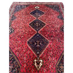 Persian crimson ground carpet, the field decorated with an indigo triple lozenge pole medallion, surrounded by all-over Boteh motifs, the guarded border with repeating geometric and floral designs