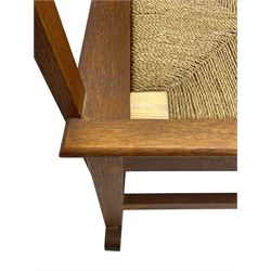 Reynold Eunson (1932–1978) for David Munro Kirkness, Kirkwall, Orkney - oak framed Orkney rocking chair, woven straw curved back, drop-in rush seat, the arm terminals with carved end scroll, on square tapering supports joined by plain stretchers, the front rail inscribed with makers marks
