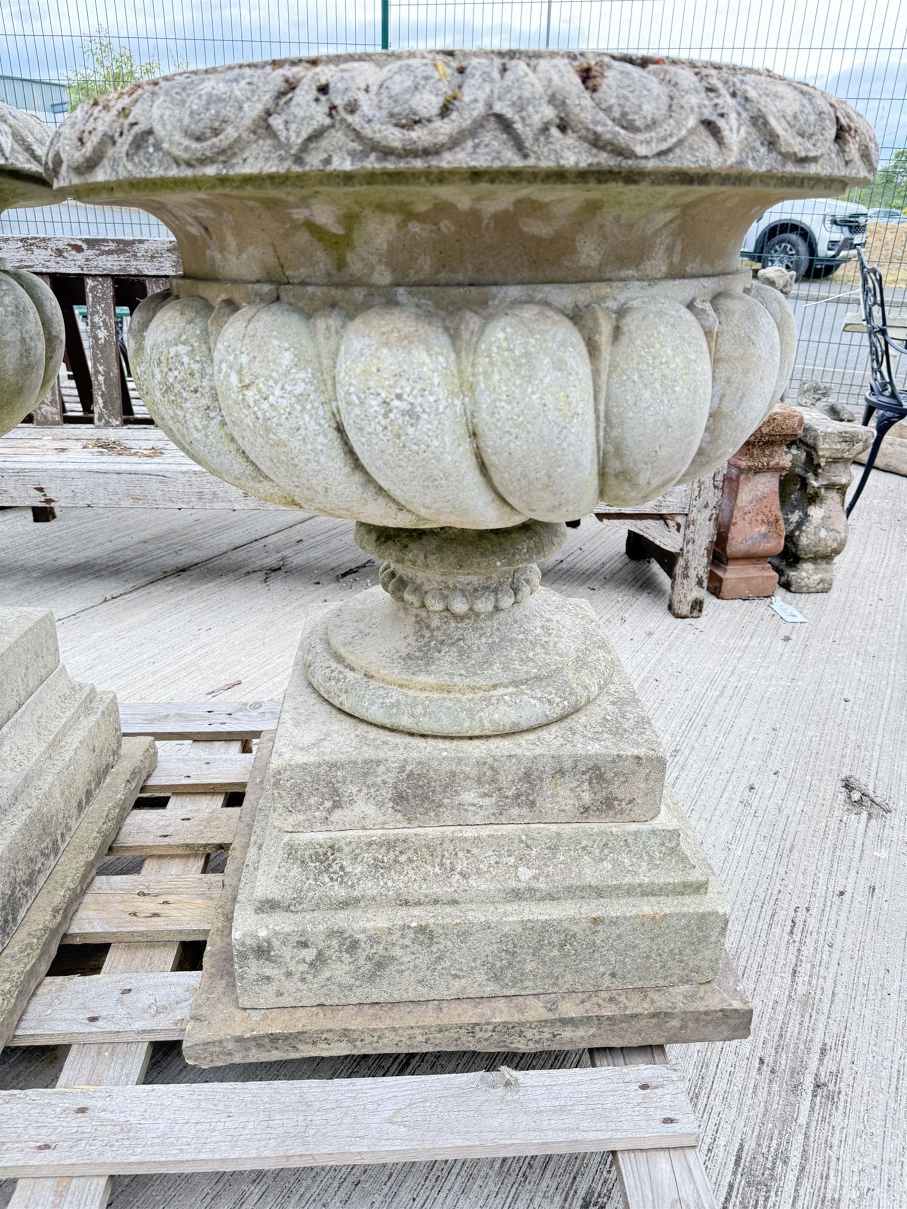 Pair of large weathered Country House Haddonstone garden urns, acanthus carved rim above gadrooned bowl, beaded detailing to the neck, raised on stepped double plinth base
