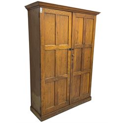 The North of England School Furnishing Company Limited Darlington - early 20th century oak school cupboard, projecting moulded cornice over two panelled doors, fitted with shelves, on chamfered plinth base 