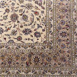 Central Persian Kashan hand-knotted carpet, ivory field densely decorated with an all-over design of scrolling floral vines and palmettes, framed by multiple borders with continuous floral meander and rosette motifs, in a palette of indigo, ivory, soft blue, sage green, rose and ochre tones, with cotton fringe ends 
