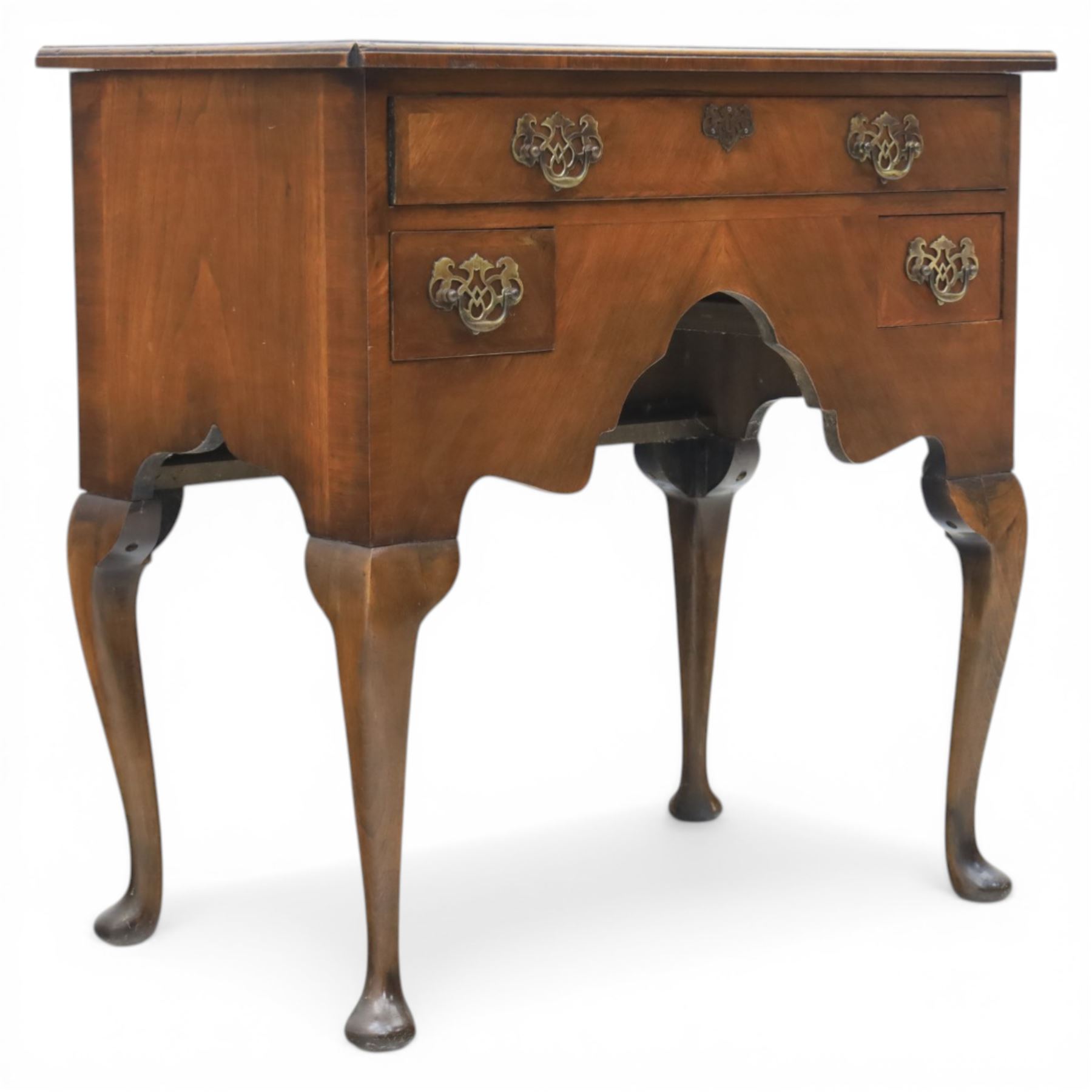 Early 20th century walnut lowboy in Queen Anne style, rectangular crossbanded top over single long drawer and two short drawers with shaped apron, fitted with brass drop handles and backplates, raised on cabriole supports terminating in pad feet
