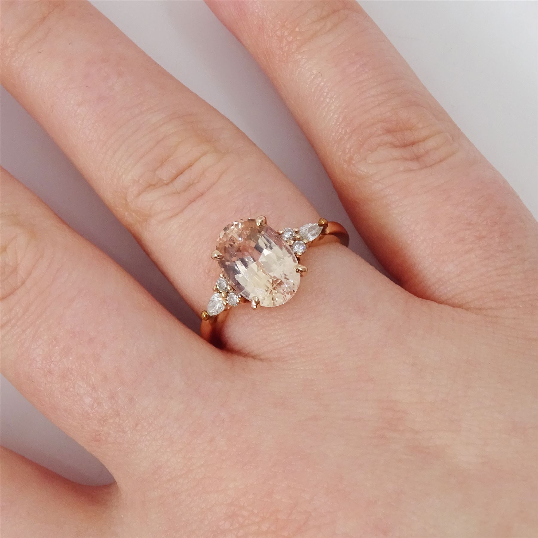 14ct rose gold pink / peach sapphire and diamond ring, single oval cut sapphire of 3.07 carat, with two round brilliant cut diamonds and a pear cut diamond set either side, stamped, total diamond weight 0.11 carat, with Gem Lab report