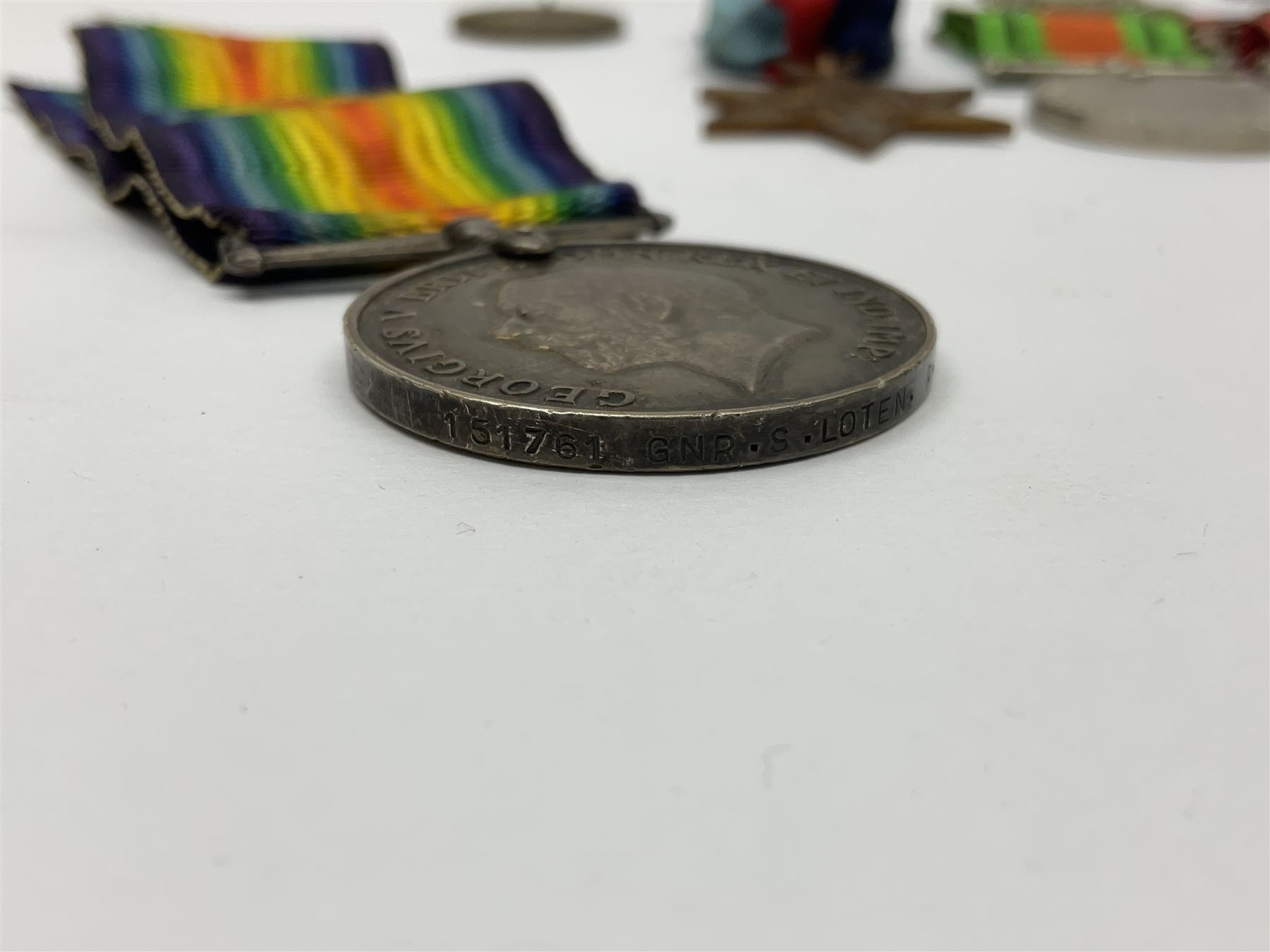 WW1 pair of medals awarded to 151761 Gnr. S. Loten R.A. with ribbons; four WW2 medals with ribbons; and small quantity of cap badges, medallions etc