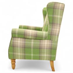 Contemporary green tartan upholstered wingback armchair, with scroll arms and loose seat cushion, raised on turned beech front supports with brass castors