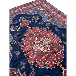 Persian Veis indigo ground carpet, the field with large pole medallion decorated with Herati motifs and surrounded by floral sprays, crimson ground border with repeating cross motifs and stylised flower heads, within guard stripes 