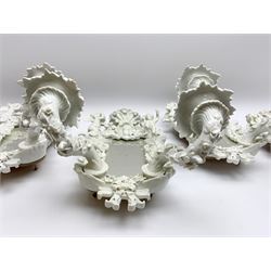 Set of four late 19th/early 20th century Continental girandole white glazed wall sconces, the shaped mirror backs within foliate detailed frames surmounted by putti, supporting two scrolling and floral encrusted branches above ribbon terminals, with blue underglaze mark to sides, H38cm
