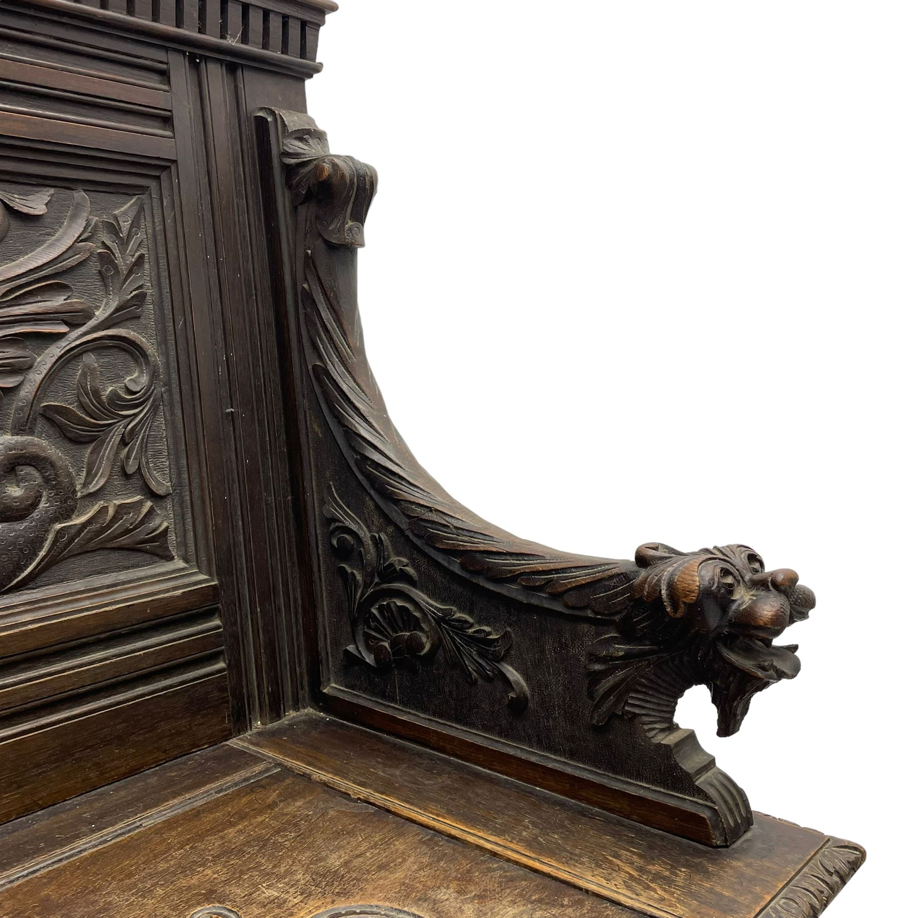 19th century oak hall bench, dentil cresting rail over moulded frame with panelled back carved with fire-breathing mythical beasts and central acanthus leaf motif, scroll carved down-sweeping arms carved with grotesque masks with scrolled foliage and shells, hinged box seat carved with scrolling foliage over panelled front with further carved foliage decoration, on paw carved front feet 
