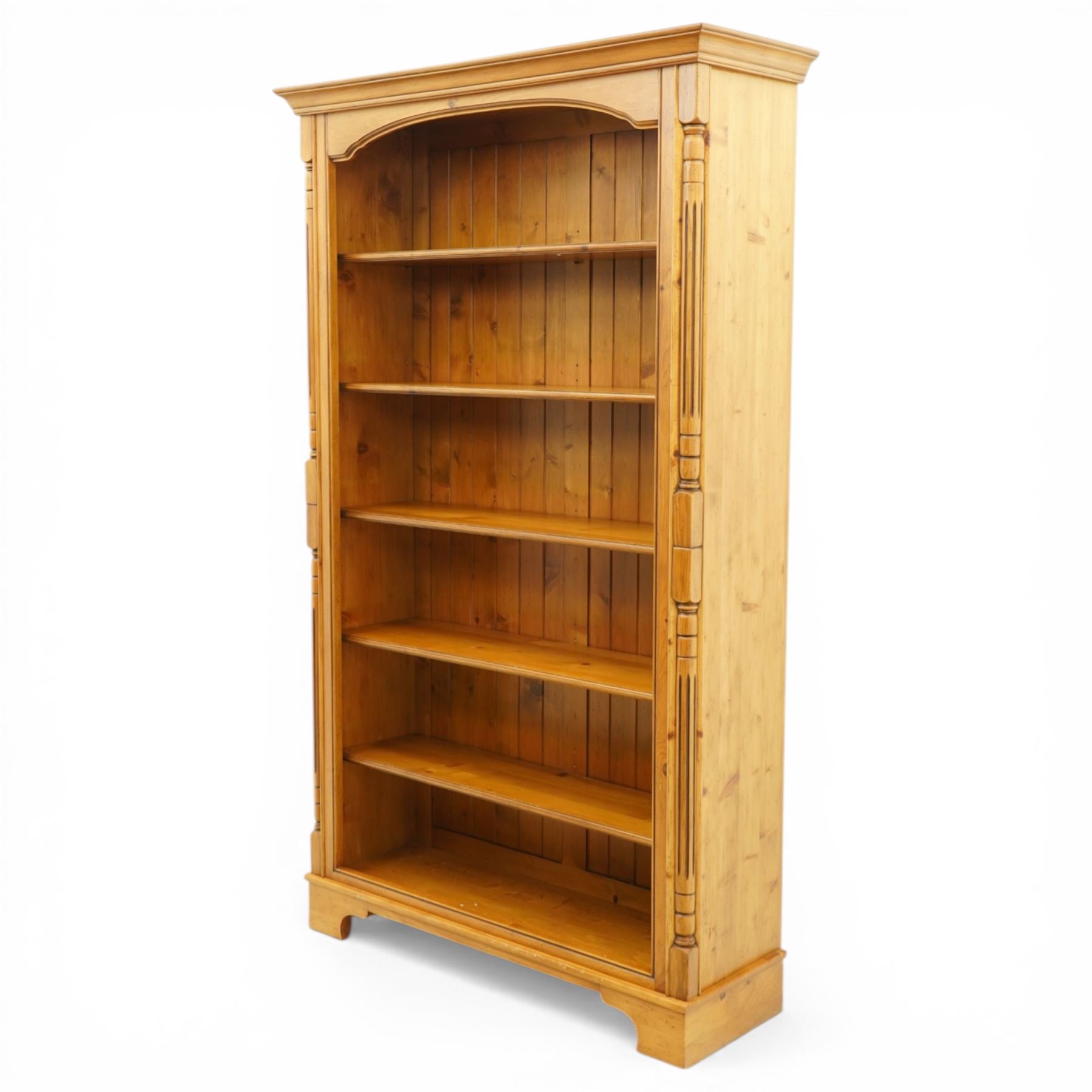 Late 20th century traditional waxed pine open bookcase, moulded cornice above a shaped frieze, open front with fixed shelves and boarded back, flanked by fluted pilasters
