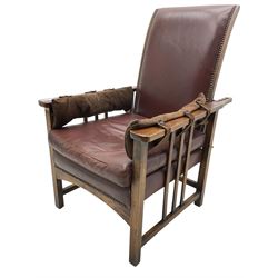 1930's hardwood-framed reclining armchair, upholstered in brown studded leather, on square supports united by horizontal and vertical stretchers, arched middle rail