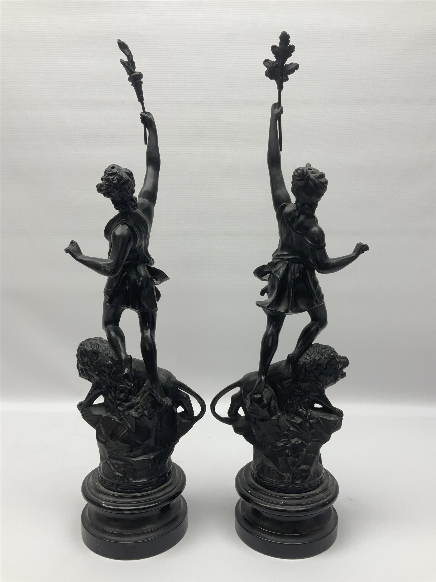 Pair of spelter figures, Le Force and Le Pouvoir, modeled as figures standing on lions, arms held aloft, H51cm 