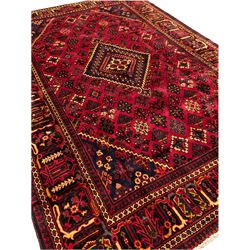 Persian red ground rug, with central stepped lozenge surrounded by plant motifs, the border decorated with a series of stylised motifs with guard bands 