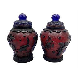 Two Chinese Peking glass baluster vases with covers, the blue overlay carved with insects, fish and foliate motifs on red ground, with seal mark beneath, H13cm