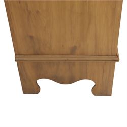 Edwardian stained pine dressing chest, the moulded top over three graduating drawers with pressed brass handles, shaped apron and bracket feet, the mirror back with rectangular plate on pivot supports, flanked by pierced Gothic style uprights with small corner shelves