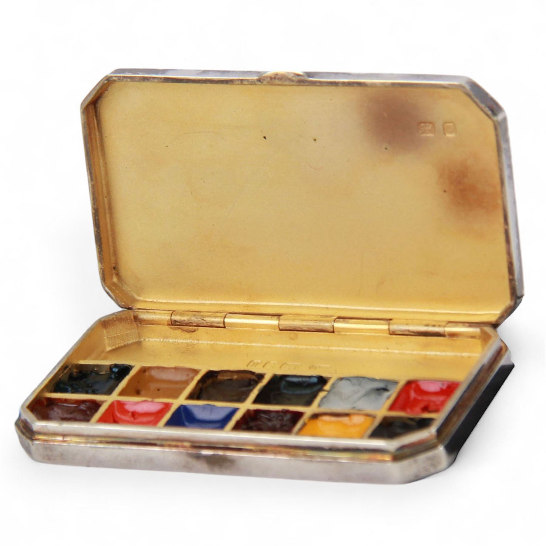 Modern silver miniature paint box, of plain rectangular form with canted corners, the hinged cover lifting to reveal a compartmented gilt interior containing twelve paints, hallmarked Sarah Jones, London 1986, L6cm