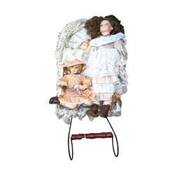 Three porcelain dolls and a wicker dolls pram with lace cover, pram handle H79cm