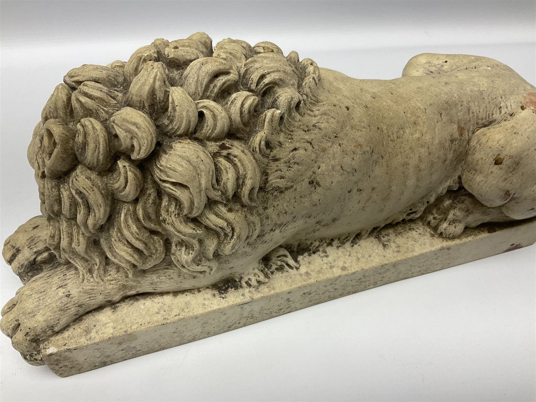 Two early 20th century reconstituted stone Grand Tour or Chatsworth House type lions after Antonio Canova, each modelled in recumbent pose upon a rectangular plinth, signed to plinth Dilettanti, each approximately L31cm