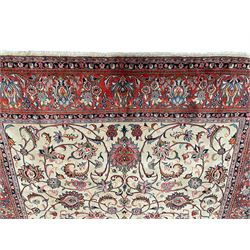 Persian Sarough ivory ground rug, the field decorated with curled leafy branches and palmettes, crimson ground border decorated with further palmettes and floral sprays, within guard stripes 