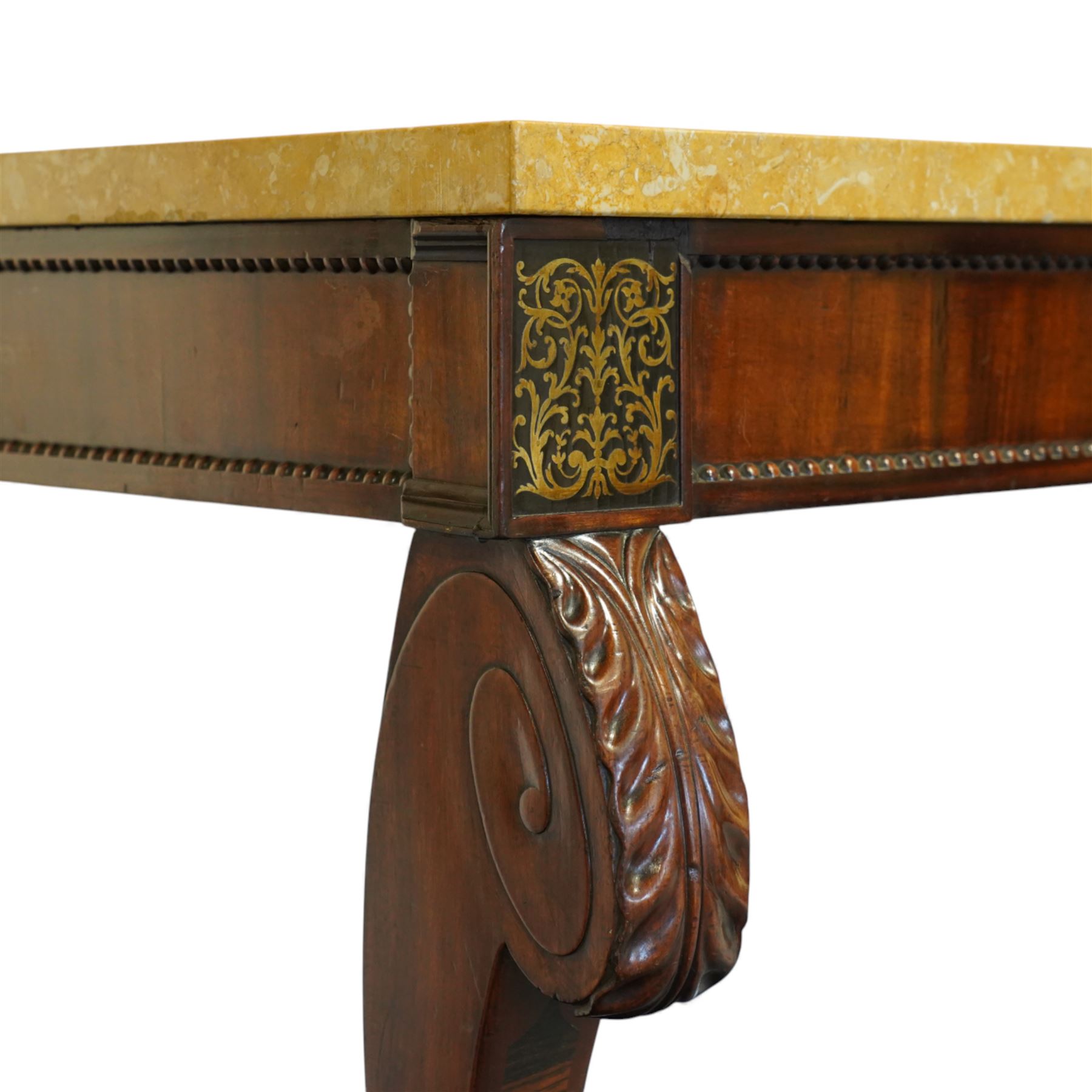 William IV mahogany and brass-inlaid marble serving table, the rectangular marble top featuring yellow tones, bordered by inlaid coloured marble bands in red and black, the frieze with brass-inlaid Boulle-inspired foliate panels on ebony, lower edge with beaded moulding, front legs inlaid with a stripped band of coromandel above carved acanthus leaves, tapering to carved lion paw feet, circa 1830