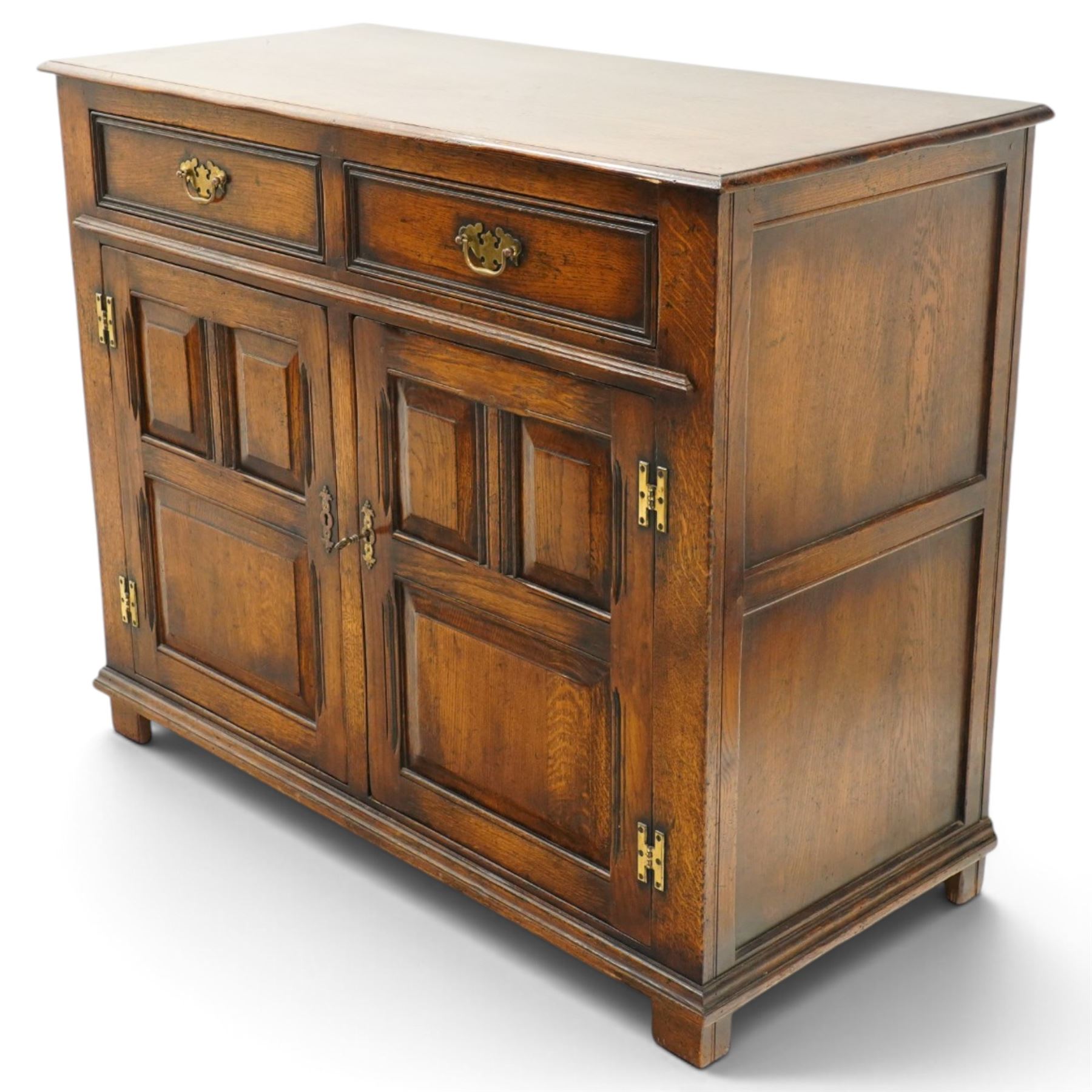 18th century style oak dresser base, rectangular moulded top over two frieze drawers with brass handles, twin panelled cupboard doors below with pierced brass escutcheons, on stile feet