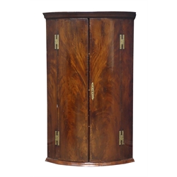  George lll mahogany bow front corner cupboard with moulded cornice above a pair of crossbanded matched curl veneer doors with brass H hinges, enclosing three shelves, H95cm, W59cm, D40cm   