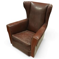 Early to mid 20th century pair of wingback armchairs, upholstered throughout in chocolate brown leather, the backs with deep wings, square padded arms with piped seams, loose seat cushions over solid bases