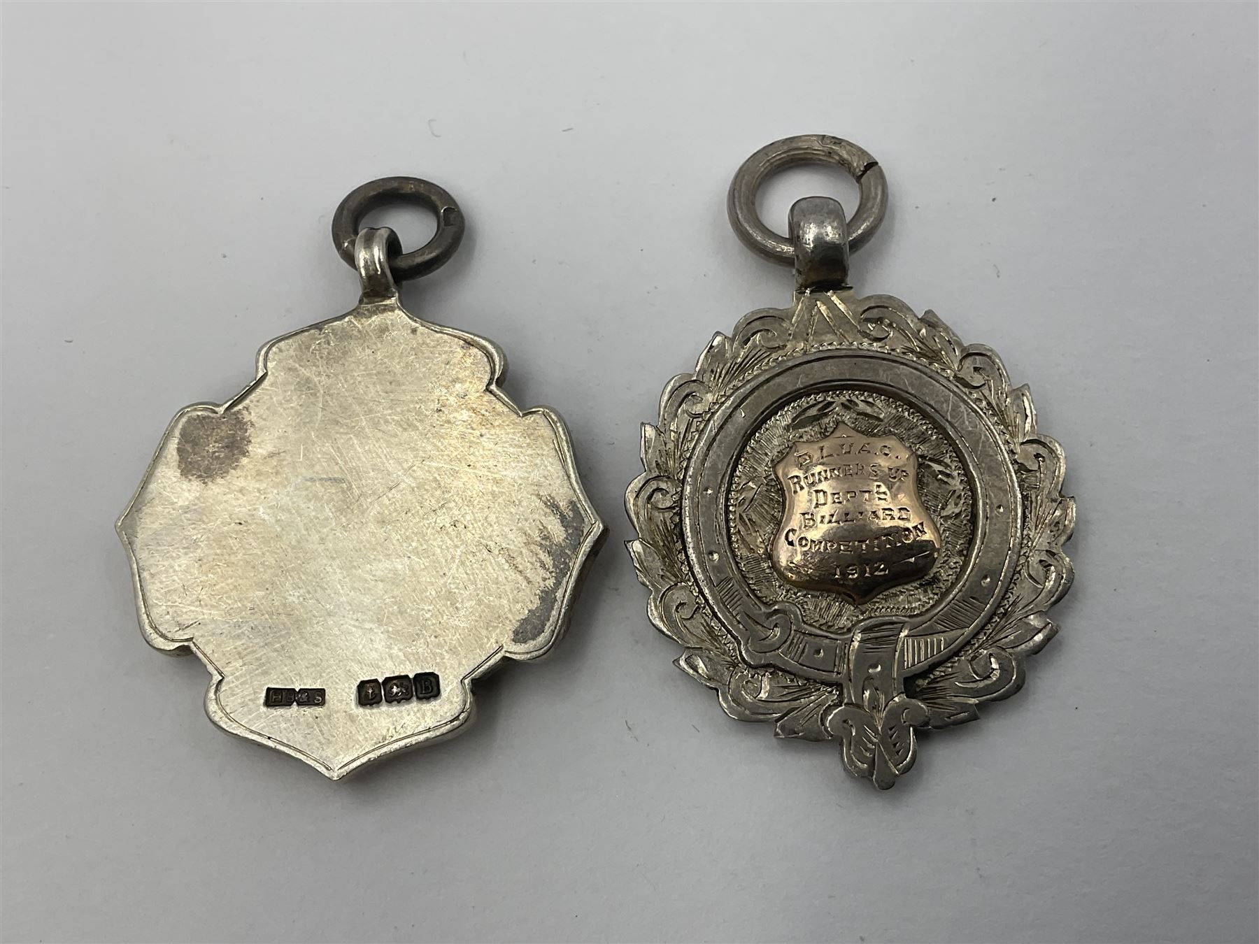 Seven early 20th century silver gold faced cartouche fobs, to include a circular example, with rose gold border and cartouche within an embossed yellow gold border, engraved verso, and a double sided example, all hallmarked with various dates and makers
