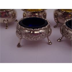 Pair of Victorian silver open salts, of cauldron form, with repousse and chased floral decoration, upon three trefid feet, hallmarked William Hutton & Sons, Sheffield 1883, with blue glass liners, together with a set of four Victorian silver open salts, of circular form, with C scroll rim and upon three pad feet, two with gilded interiors, hallmarked Edward Barnard & Sons Ltd, London 1900, tallest H3.5cm