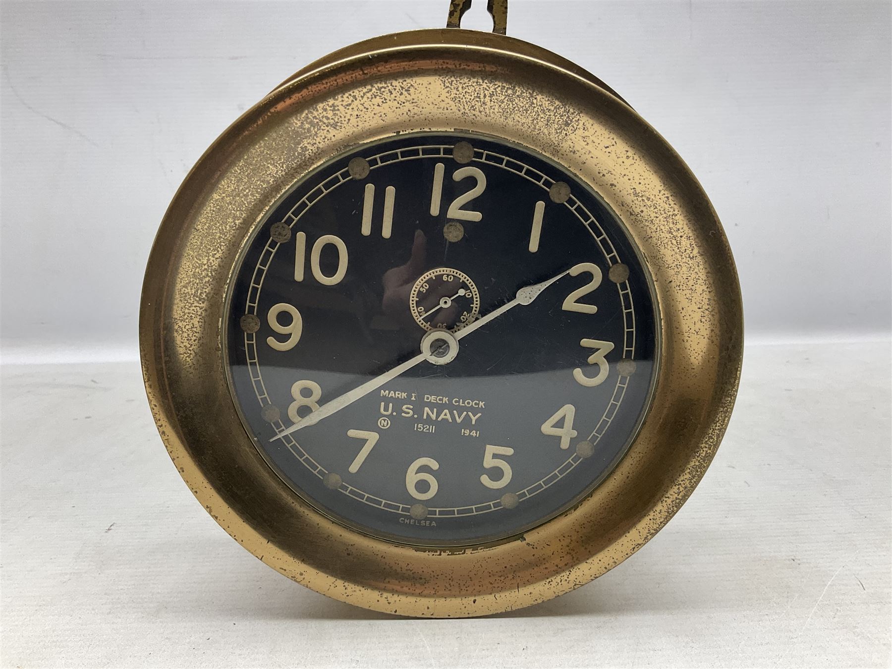 WWII period US Navy Mark I deck clock, the black circular dial with Arabic numerals,  luminous dot markers and subsidiary seconds dial marked 'Mark I Deck Clock U.S. Navy 15211 1941', in bronze bulk head case D20cm; and a Loose-Wiles Biscuit Company octagonal tin decorated with nine different US Warships (2)