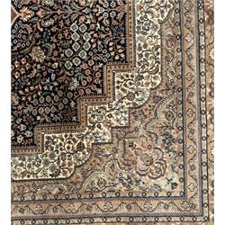 Large Persian indigo ground rug, the busy field decorated with trailing branches and flower heads, peach border decorated with palmettes -