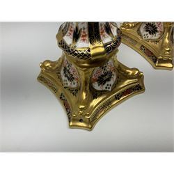 Mid 20th century Royal Crown Derby Old Imari 1128 pattern candlesticks, each with shaped drip tray affixed to squat socket, upon spreading stem and canted square base with gilt dolphin edges, with printed marks beneath including Roman numeral year cypher for 1968, H26.5cm