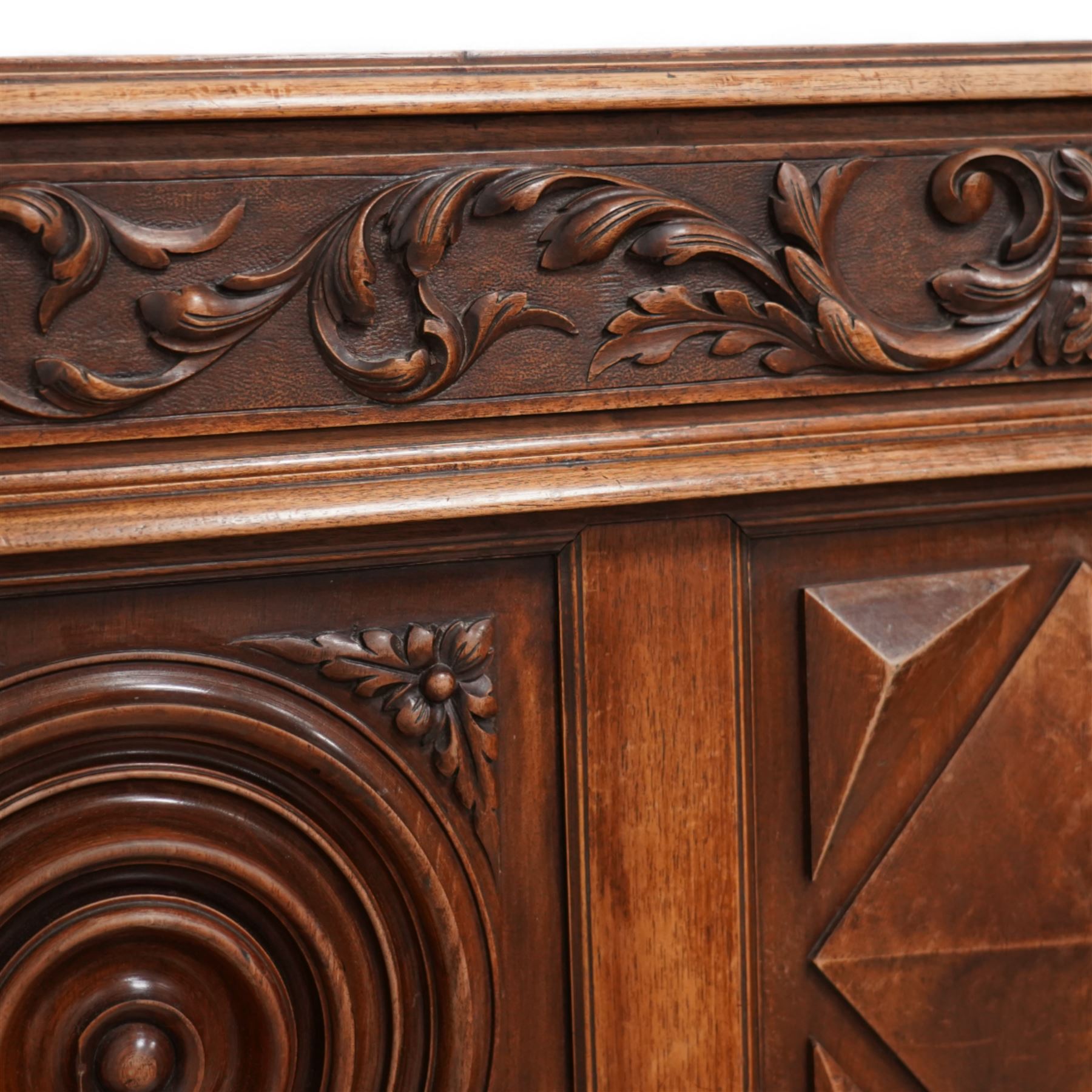 Late 19th century French walnut double bedstead, the panelled headboard with curling foliage carved frieze over concentric turned roundels and faceted mounts, lion mask carved rails with applied panelled mounts, matching footboard with lower carved lion mask 