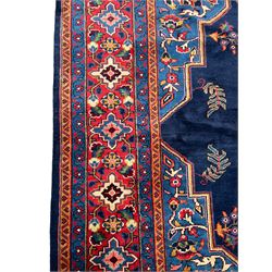 Persian Veis indigo ground carpet, the field with large pole medallion decorated with Herati motifs and surrounded by floral sprays, crimson ground border with repeating cross motifs and stylised flower heads, within guard stripes 