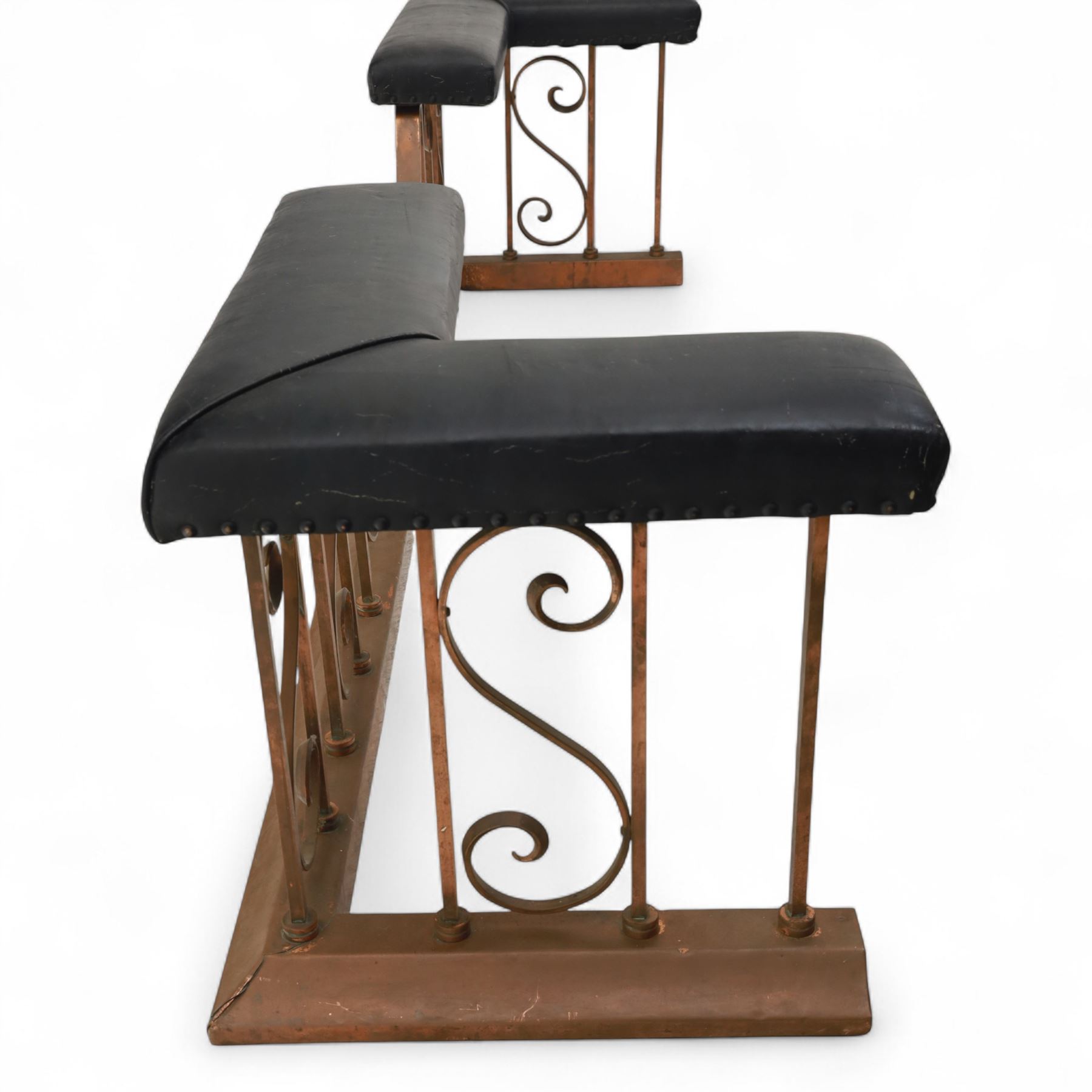 Early 20th-century Arts & Crafts copper club fender, of long serpentine form, scrolling uprights and a shaped centre support, the top rail fitted with four upholstered padded seat sections, raised on a stepped plinth base, inner dimensions 192x43cm 
