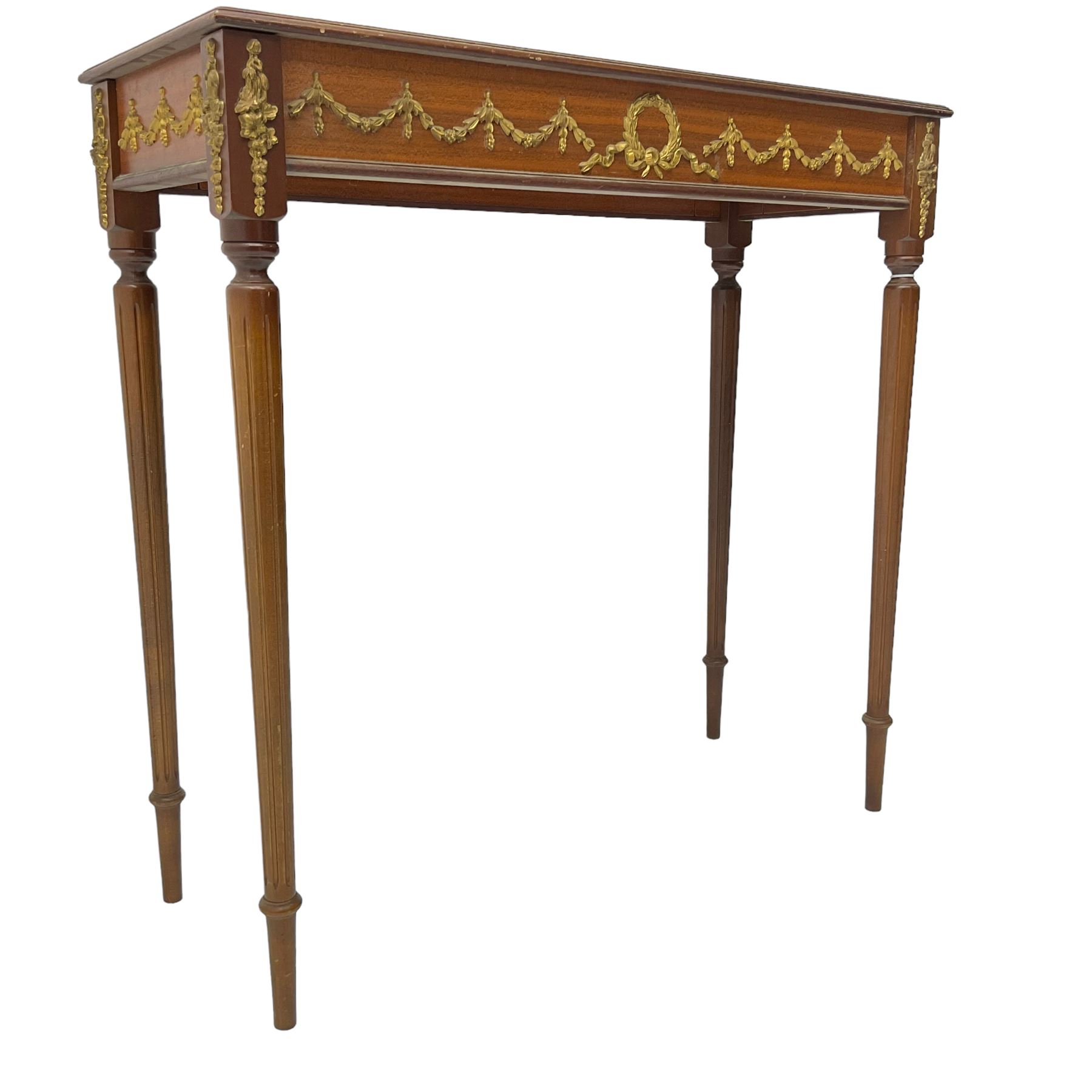 Early 20th century mahogany side table, inset amber leather surface, frieze decorated with applied gilt festoons and central wreath, on tapering fluted supports
